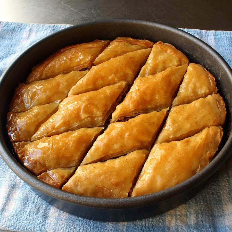 close up view of sliced Baklava in a round baking dish on a kitchen towel