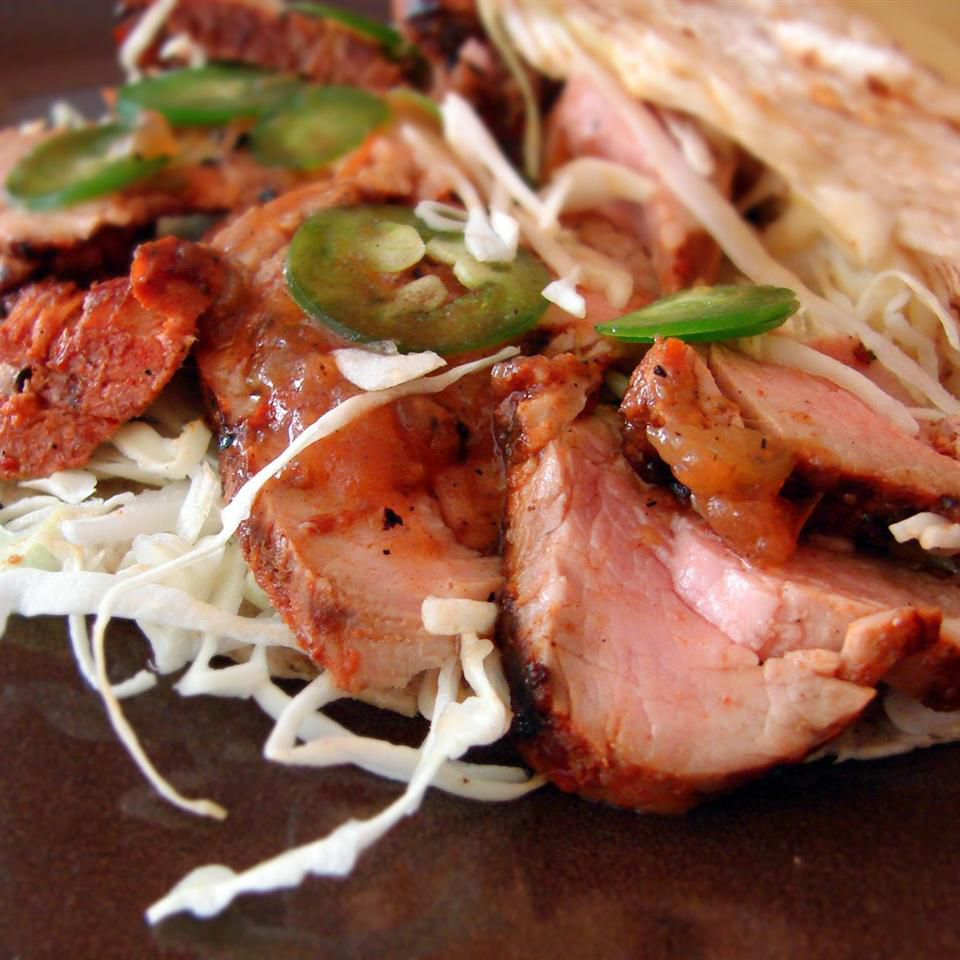 close up view of Grilled Pork Tacos al Pastor with cabbage and jalapeno slices on a plate