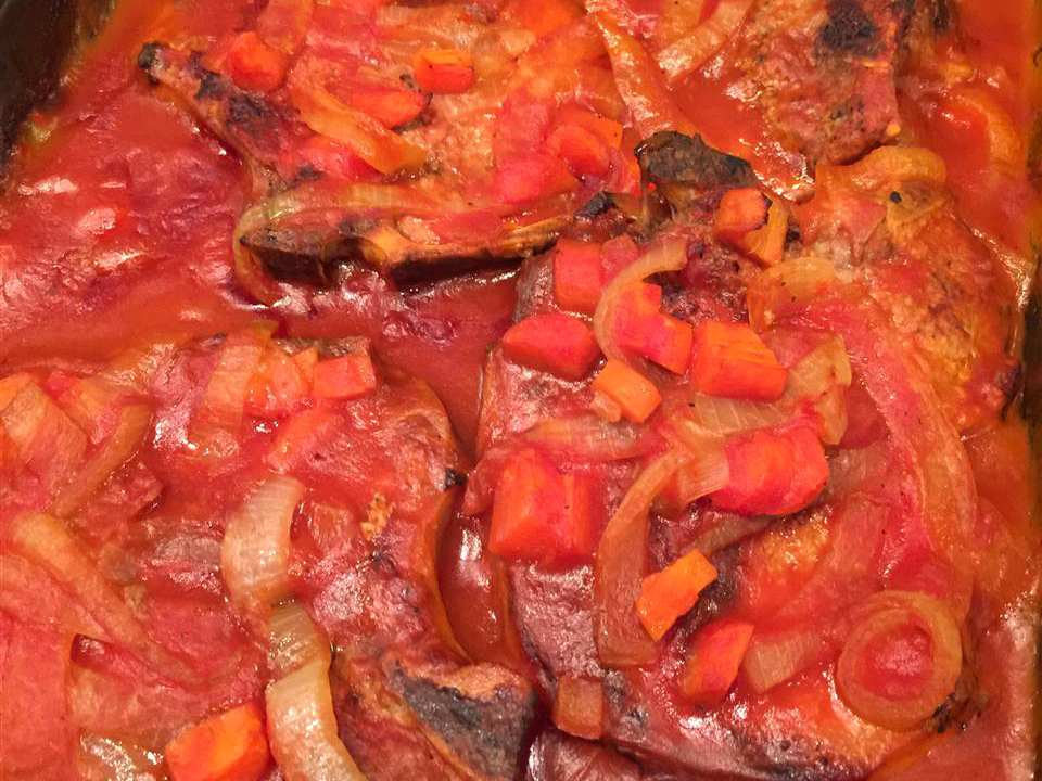 close up view of Pork Chops in Red Sauce in a baking dish