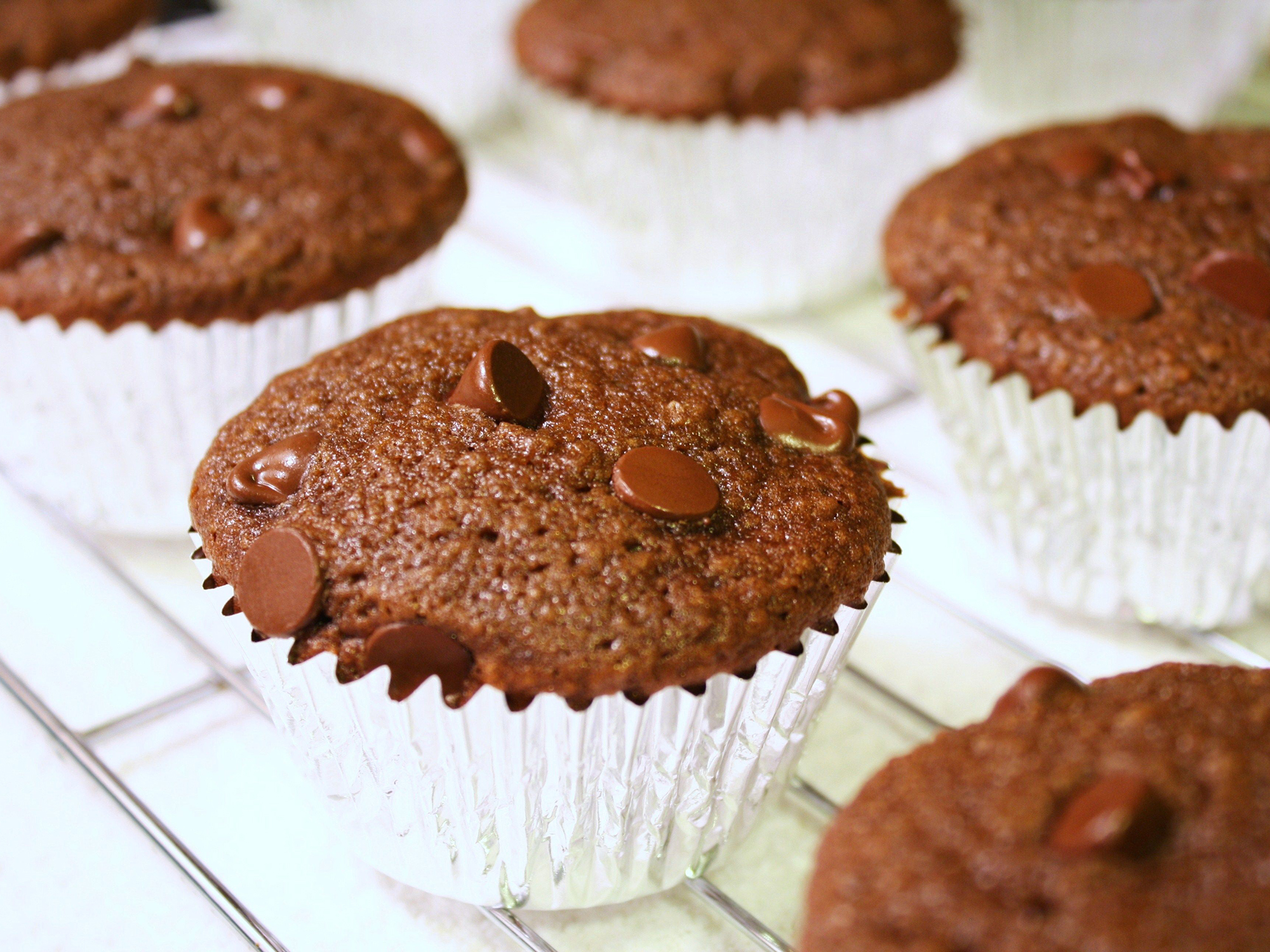 close up view of Chocolate Applesauce cupcakes in muffin liners on a cooling rack