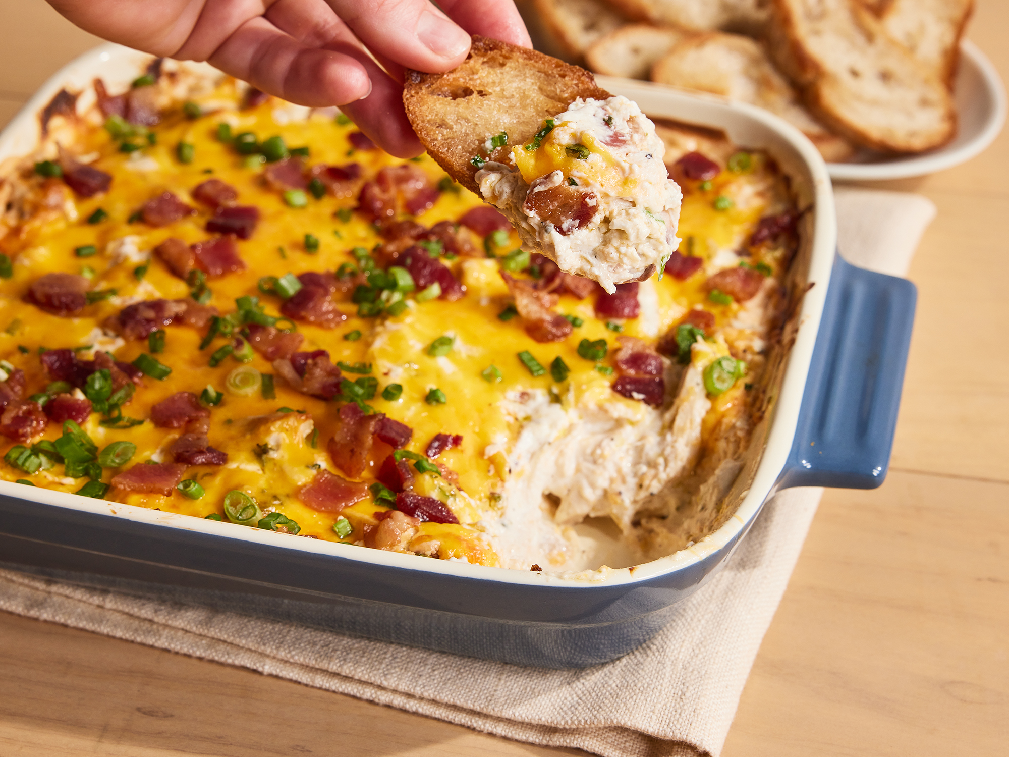 close up on a casserole dish of chicken bacon ranch dip with a scoop being taken out