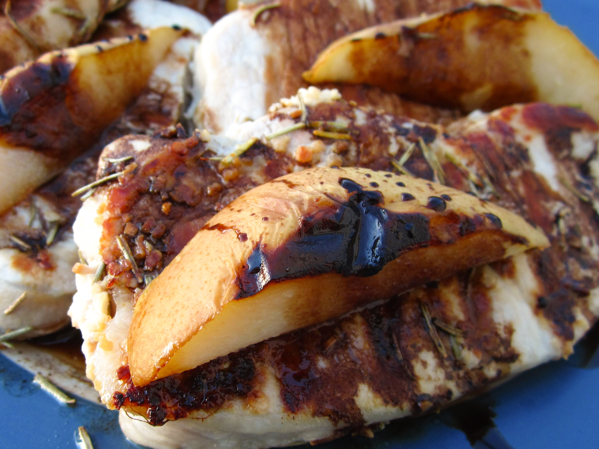 close up view of Grilled Pork Chops with Balsamic Caramelized Pears on a blue plate