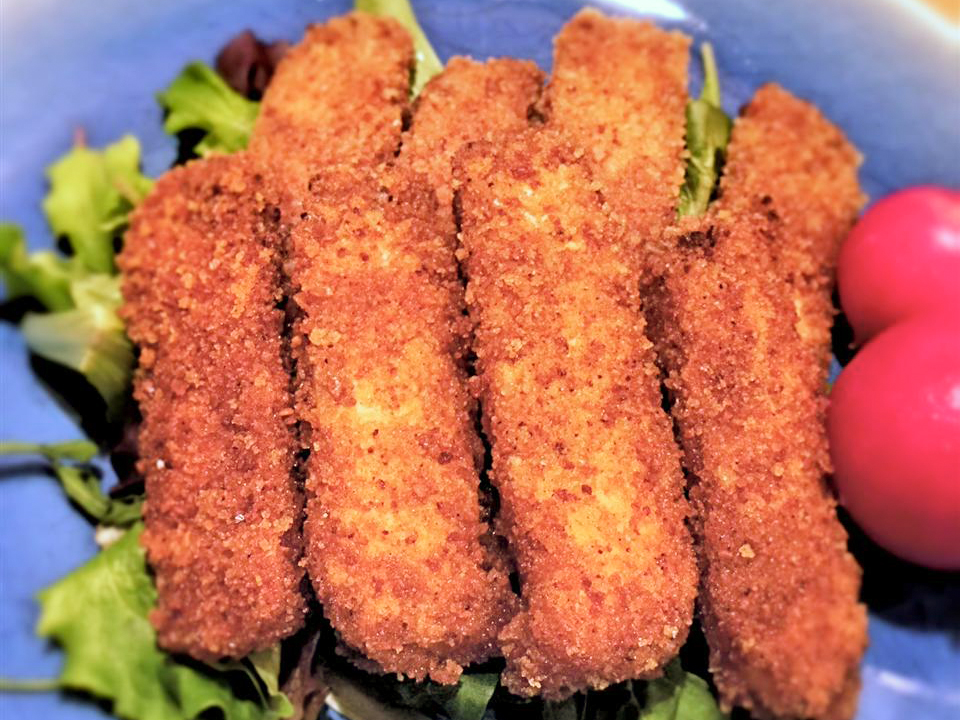 close up view of Vegan Breaded Tofu nuggets on top of a salad, on a blue plate