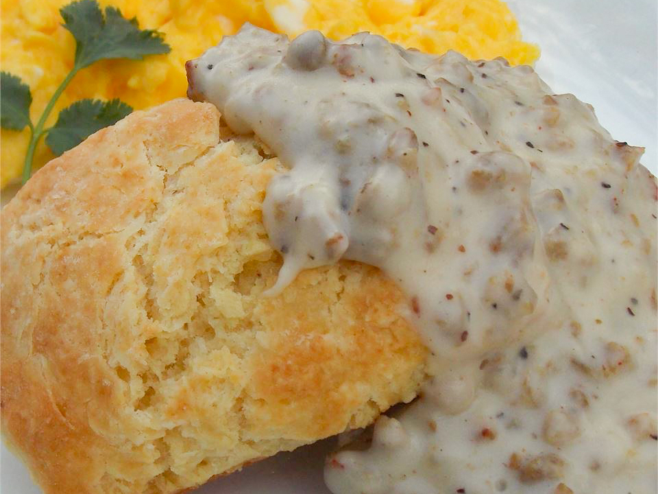 close up view of Creamy Biscuits and Gravy| served with scrambled eggs and fresh herbs