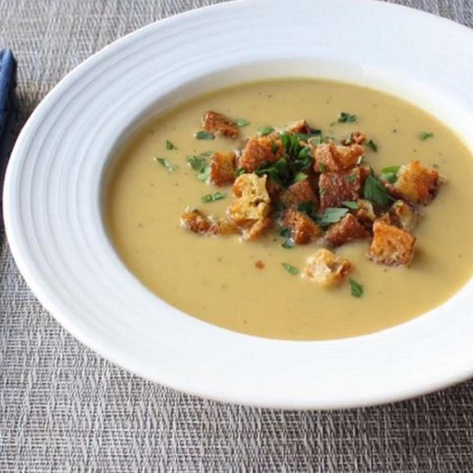 close up view of Tuscan Bean Soup garnished with croutons and fresh herbs in a white bowl
