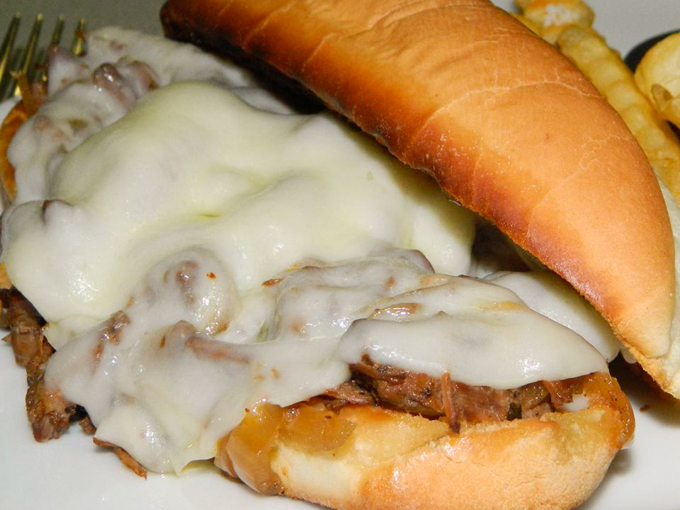 close up view of French Dip sandwich with melted cheese on a plate