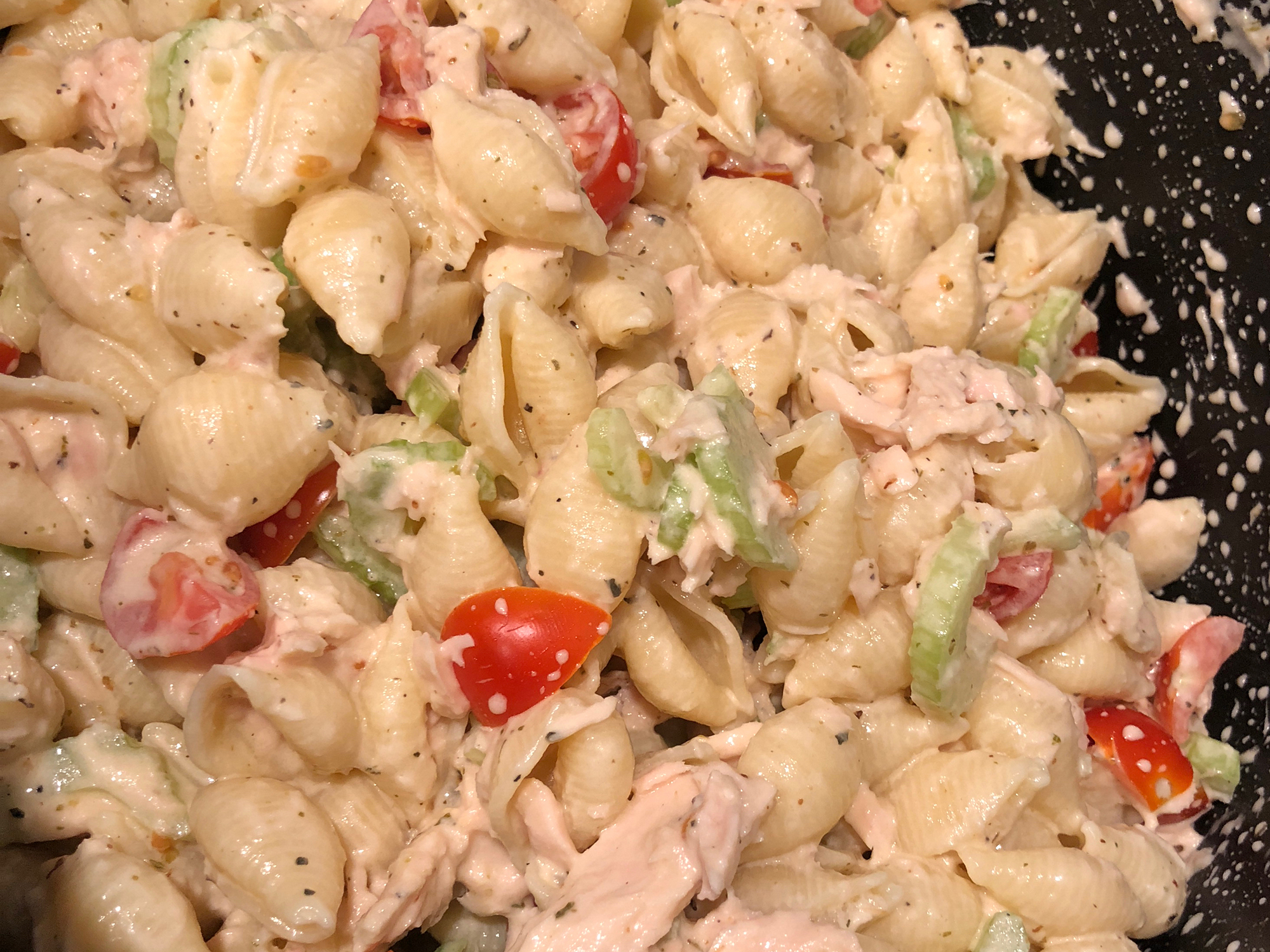 close up view of Cold Tuna Macaroni Salad with tomatoes and celery in a bowl