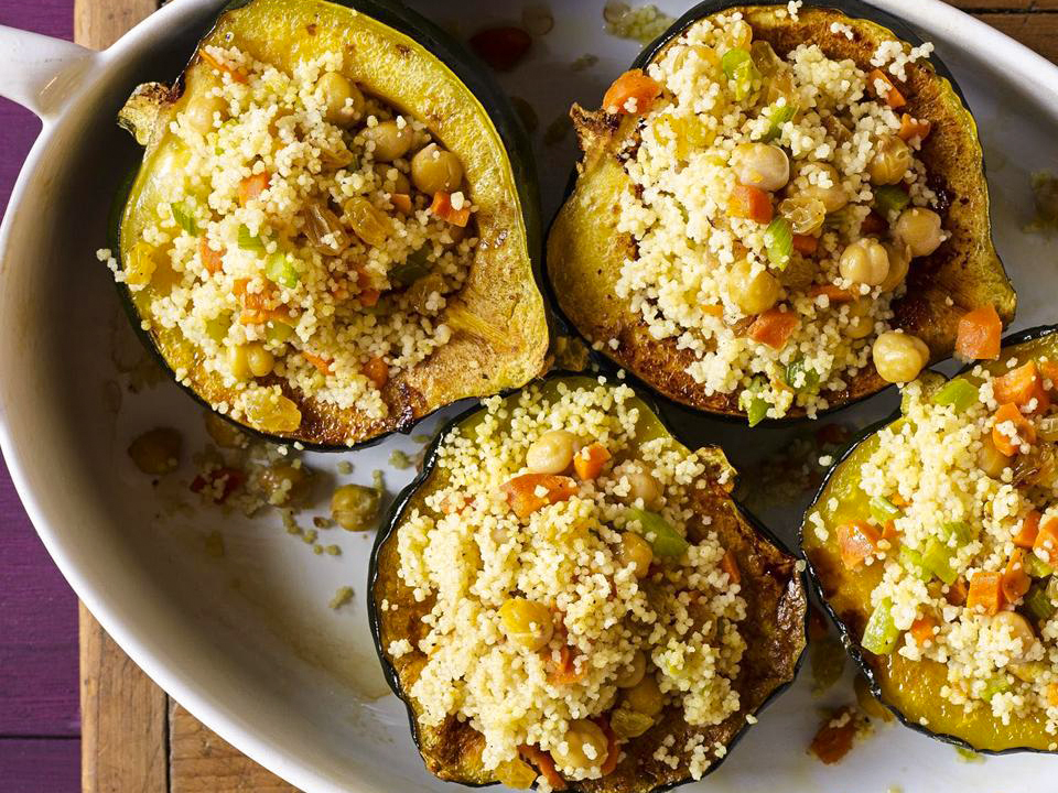 close up view of Moroccan-Style Stuffed Acorn Squash with couscous and chickpeas in a white baking dish