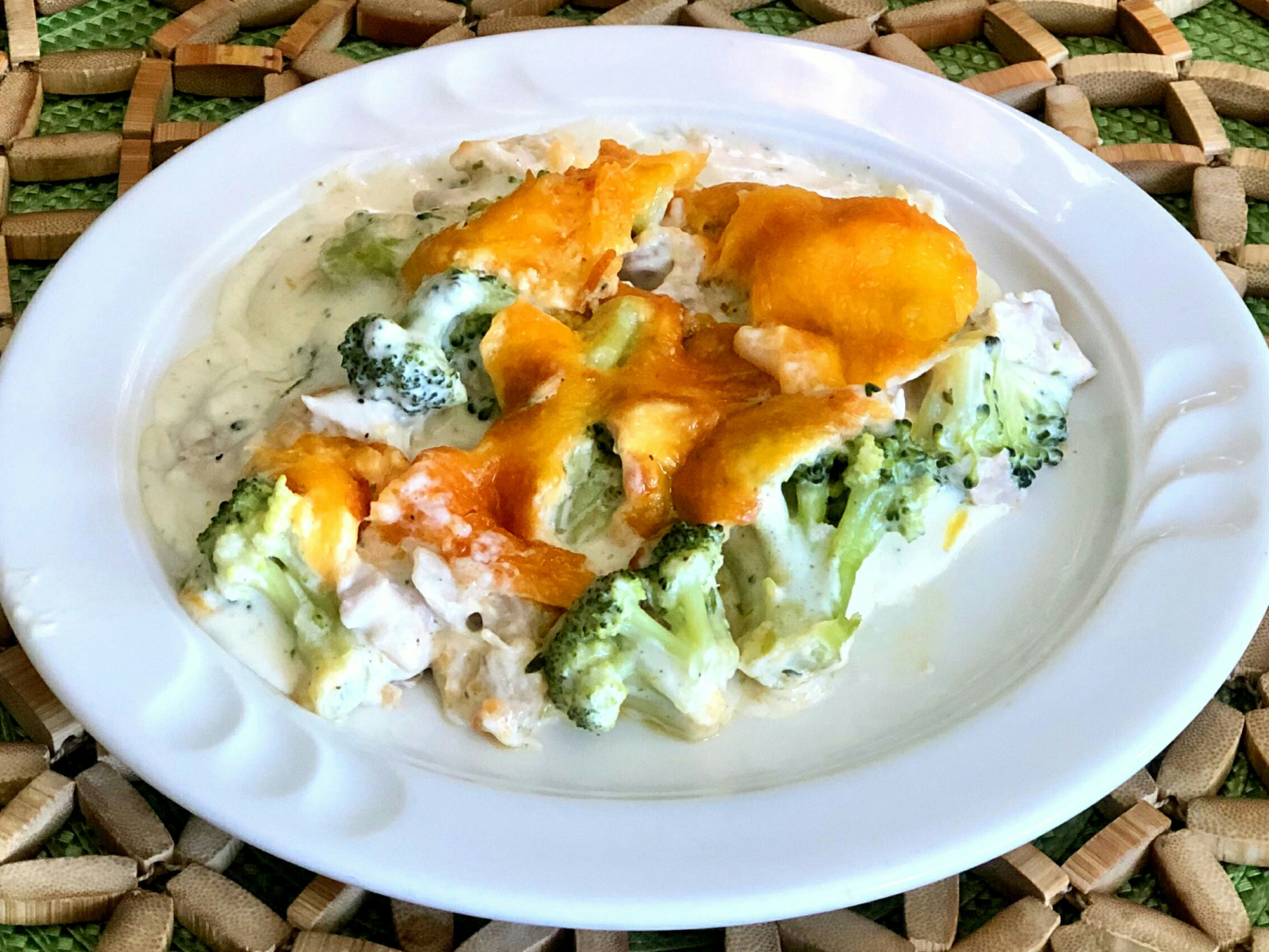 close up view of Keto Chicken-Broccoli Casserole with cheese on top, on a white plate