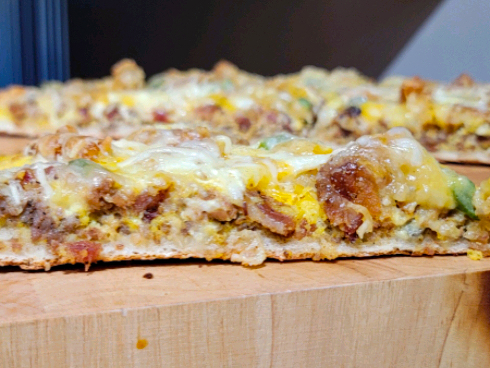 close up view of slices of Breakfast Pizza on a wooden cutting board