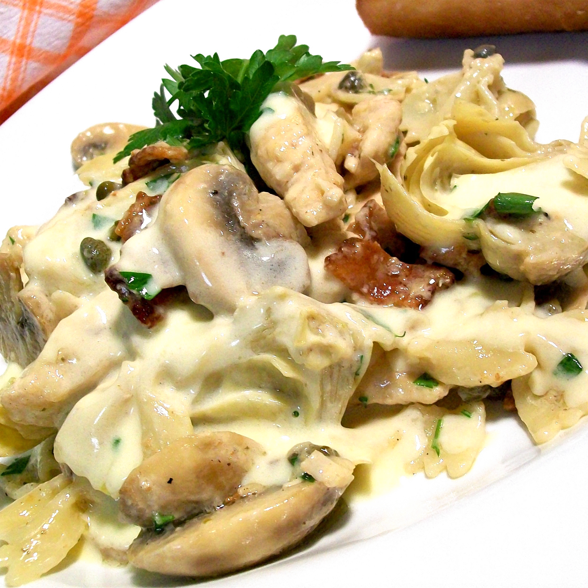 close up view of Italian Lemon Butter Chicken with mushrooms and artichokes garnished with fresh herbs on a plate