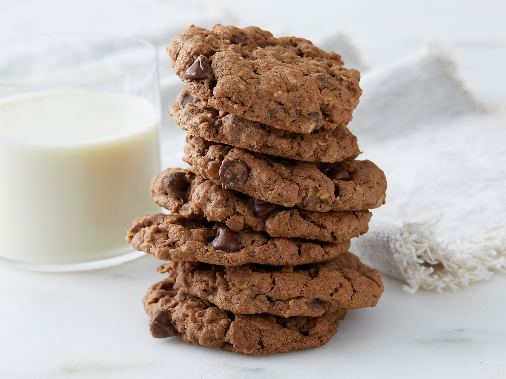 close up on a tall stack of chocolate oatmeal cookies with a side of milk