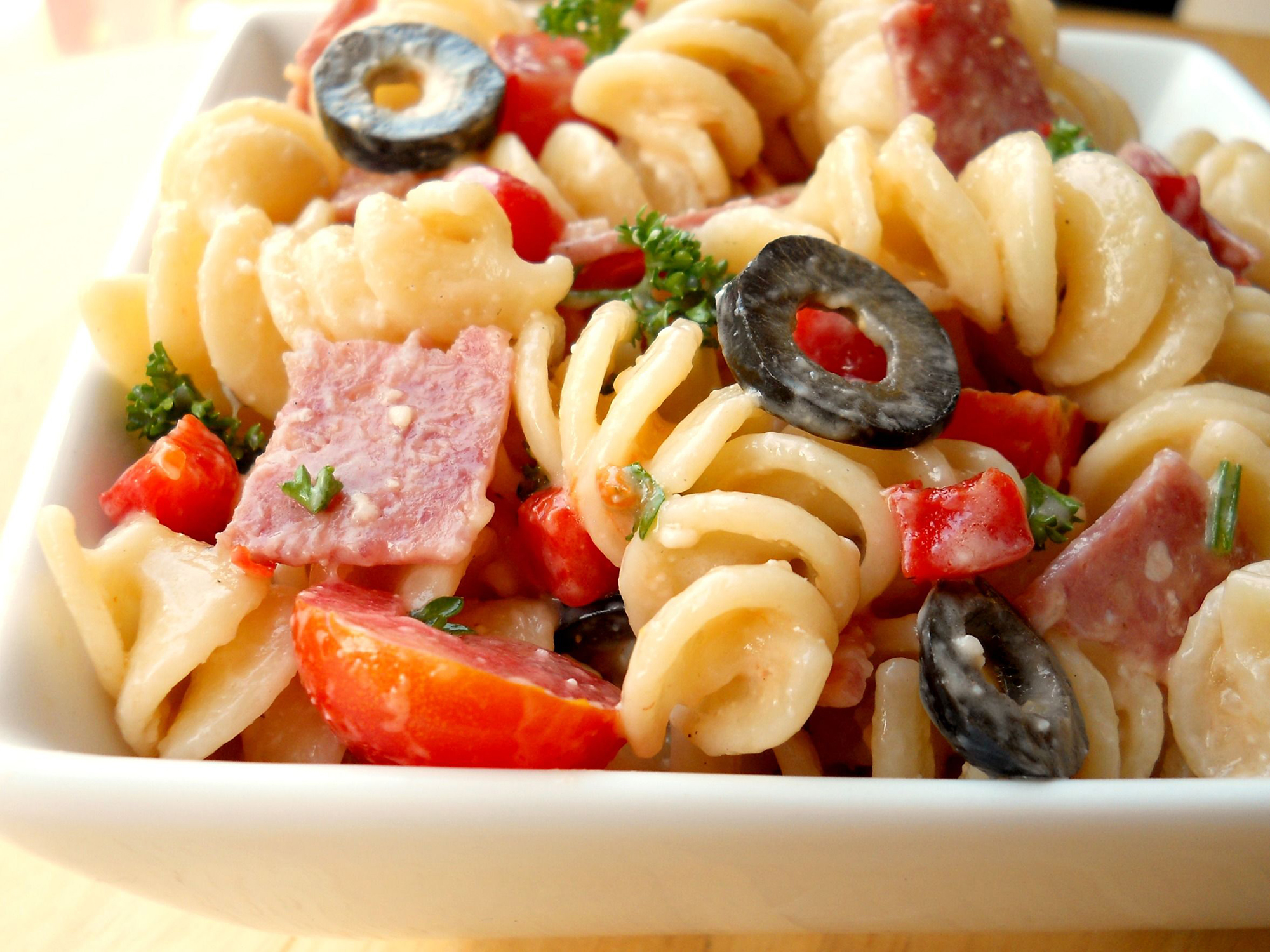 close up view of Italian Pasta Salad with salami, black olives and peppers in a bowl