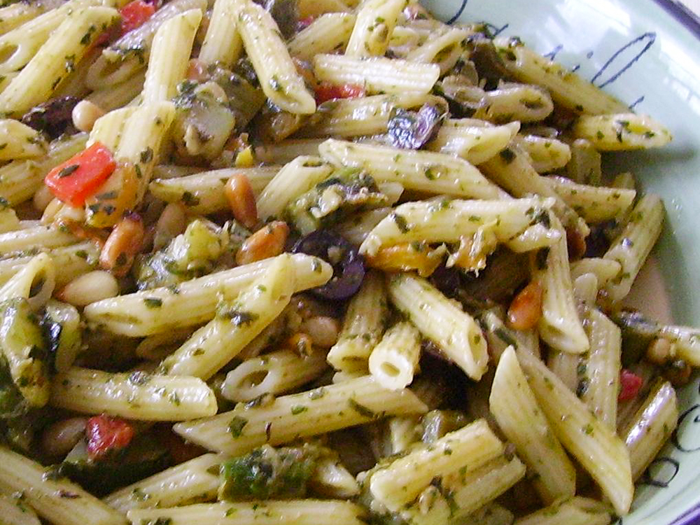 close up view of Pesto Penne Primavera with peppers and olives in a bowl