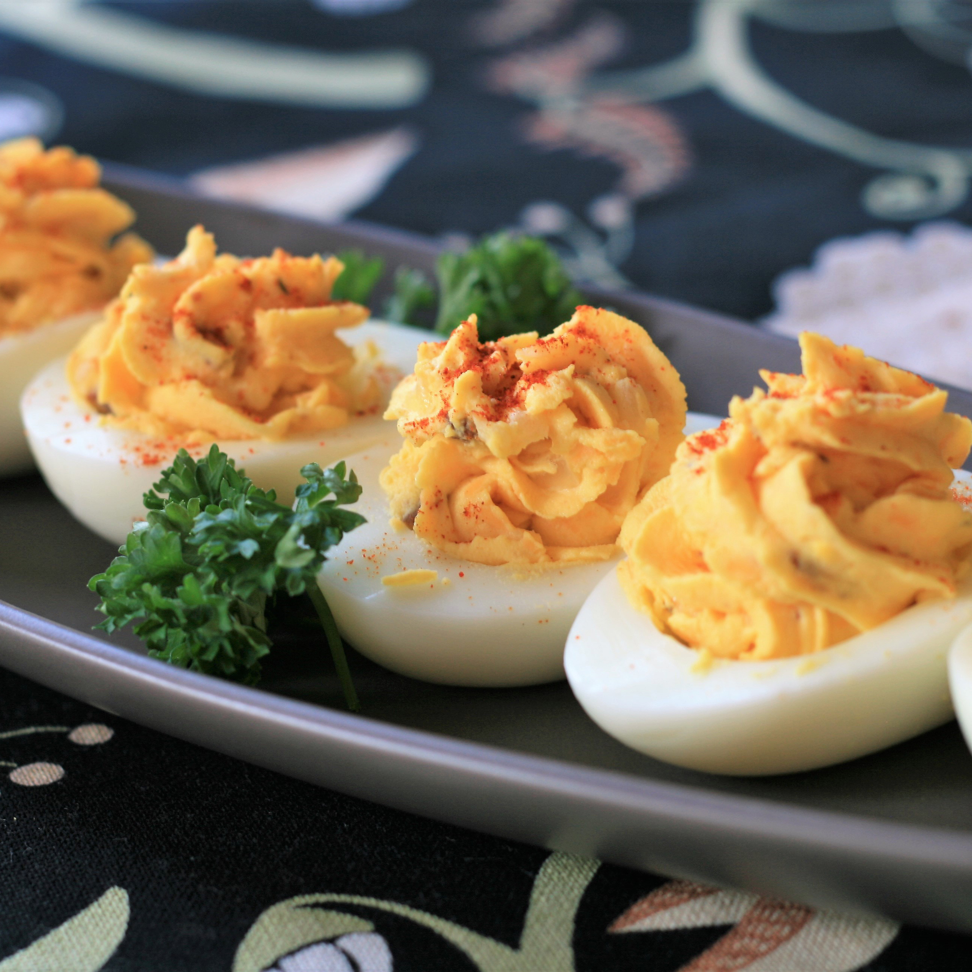 close up view of Deviled Eggs garnished with pepper and fresh herbs on a plate