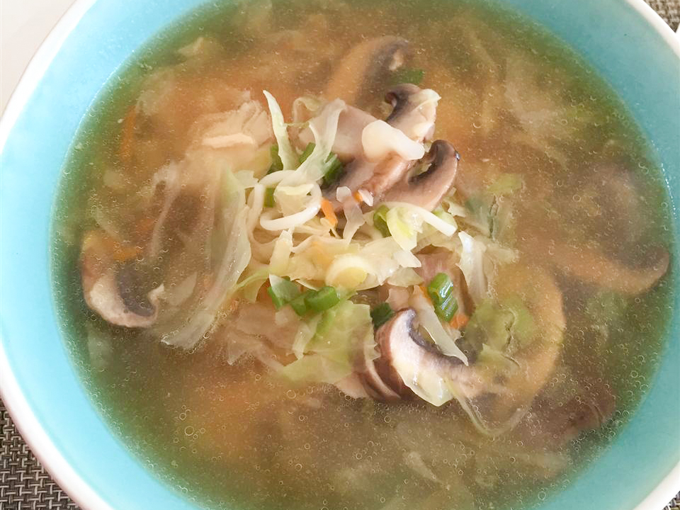 close up view of Long Soup with mushrooms and green onions in a blue bowl