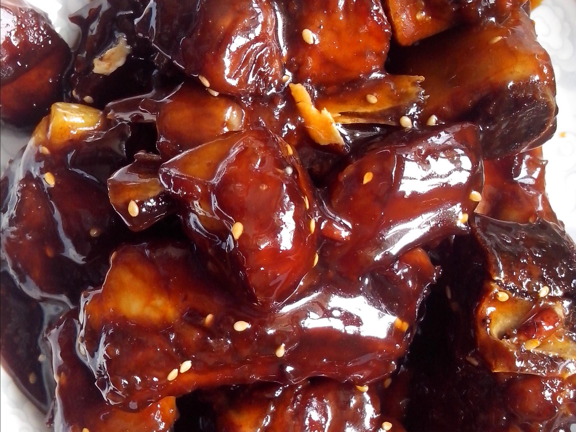 close up view of Chinese Pork Rib Tips garnished with sesame seeds on a white plate