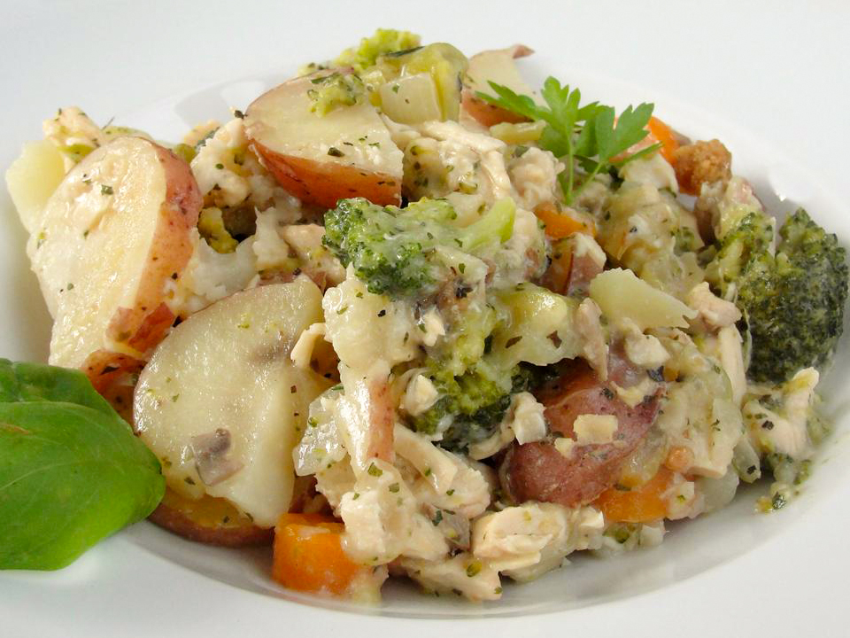 close up view of a bowl with potatoes, broccoli, and chicken, garnished with fresh herbs