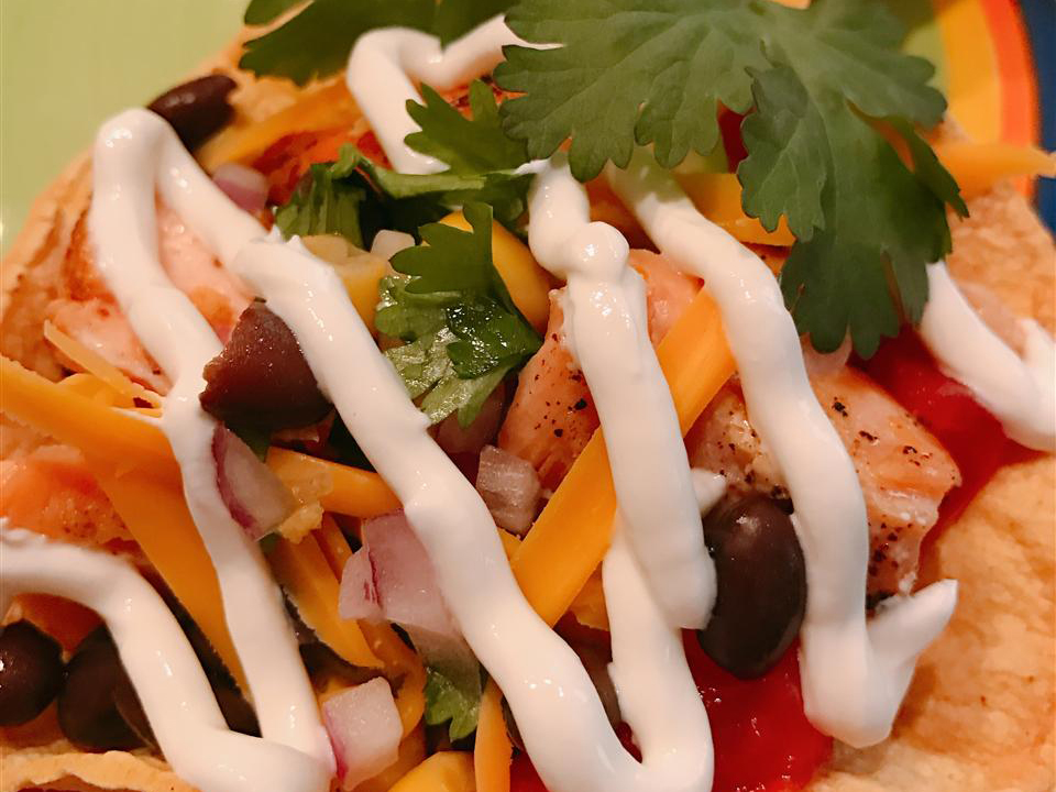 close up view of a Salmon Taco with white sauce and fresh herbs