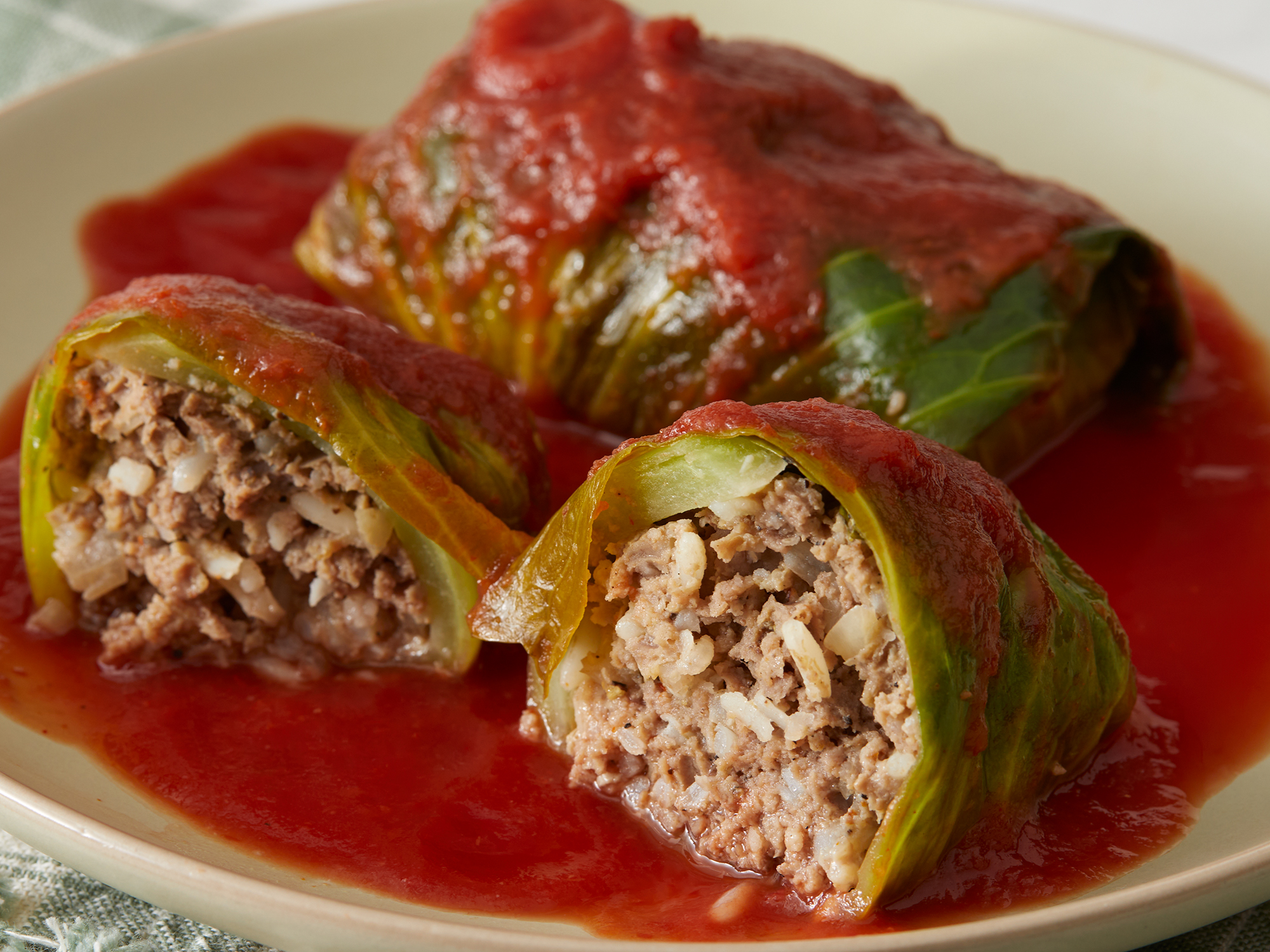 looking at two cabbage rolls, with one cut in half to see inside filling