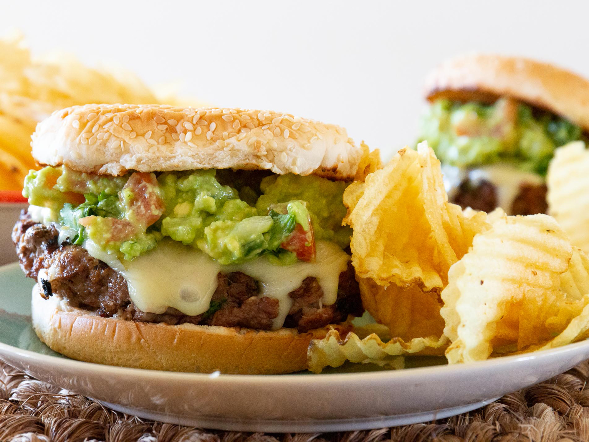 close up view of Guacamole Cilantro Lime Cheeseburgers, served with potato chips on plates