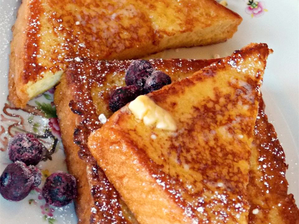 close up view of Vanilla Almond Spiced French Toast garnished with butter, blueberries and powdered sugar on a plate