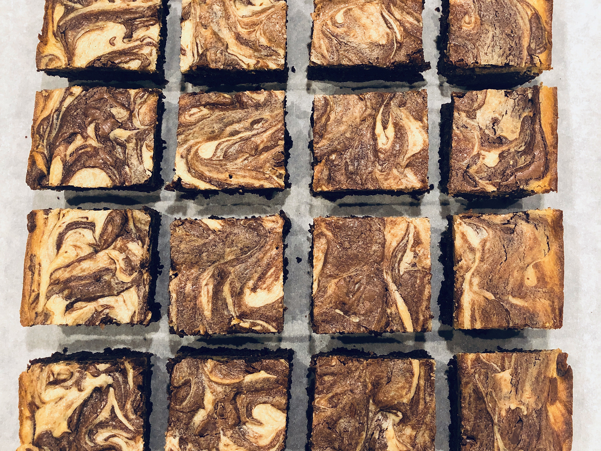 overhead view of Peanut Butter Marbled Brownies pieces on a parchment paper lined baking sheet