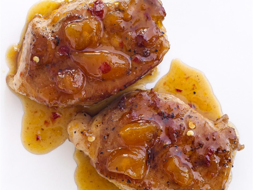 close up view of Spicy Peach-Glazed Pork Chops on a white surface