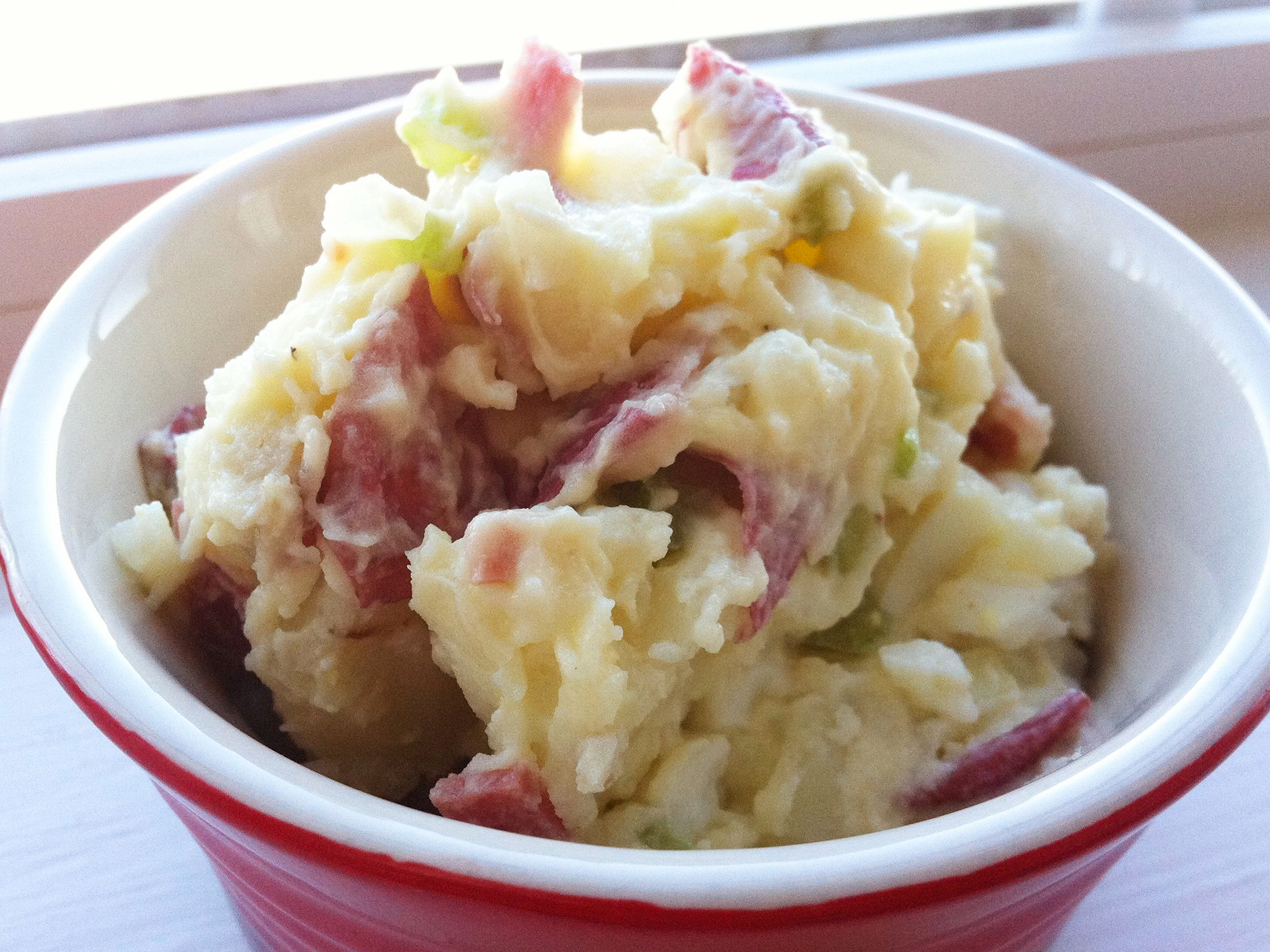 close up view of Roasted Red Potato Salad in a red and white bowl