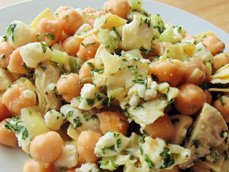 close up view of Chickpea, Artichoke, and Feta Salad with fresh herbs on a white plate