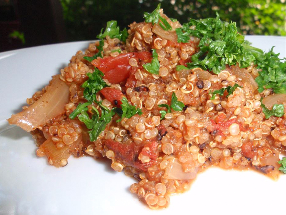 close up view of Mexican Quinoa with tomatoes, onions and fresh herbs, on a white plate
