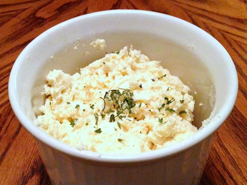 close up view of White Cheddar and Horseradish Spread garnished with herbs, in a white ramekin
