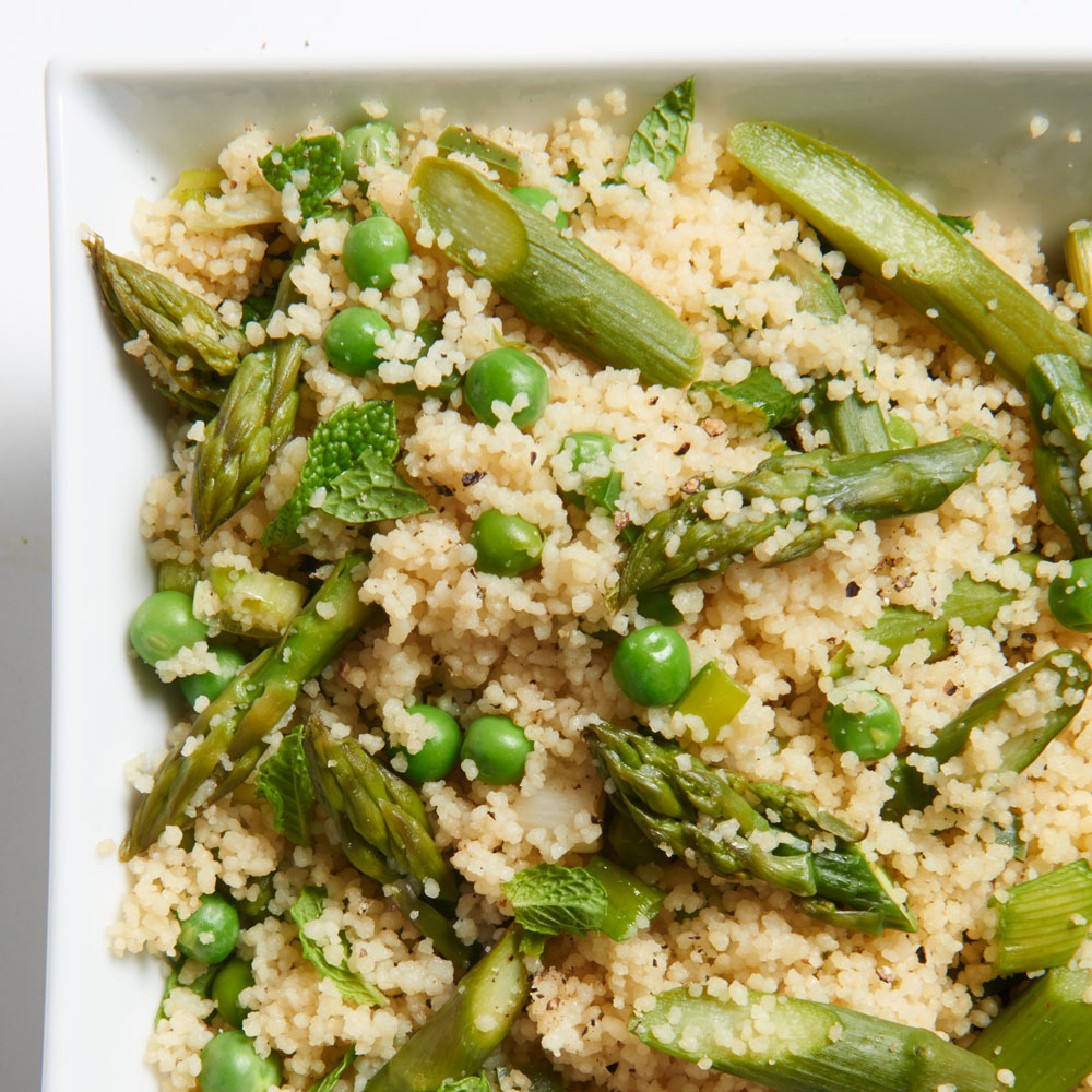 close up view of Couscous Primavera with peas, asparagus and mint on a white plate