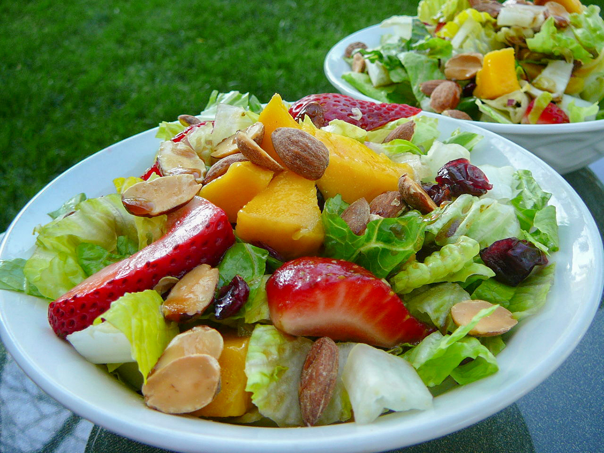 close up view of Strawberry Mango Mesclun Salad with nuts and lettuce in bowls