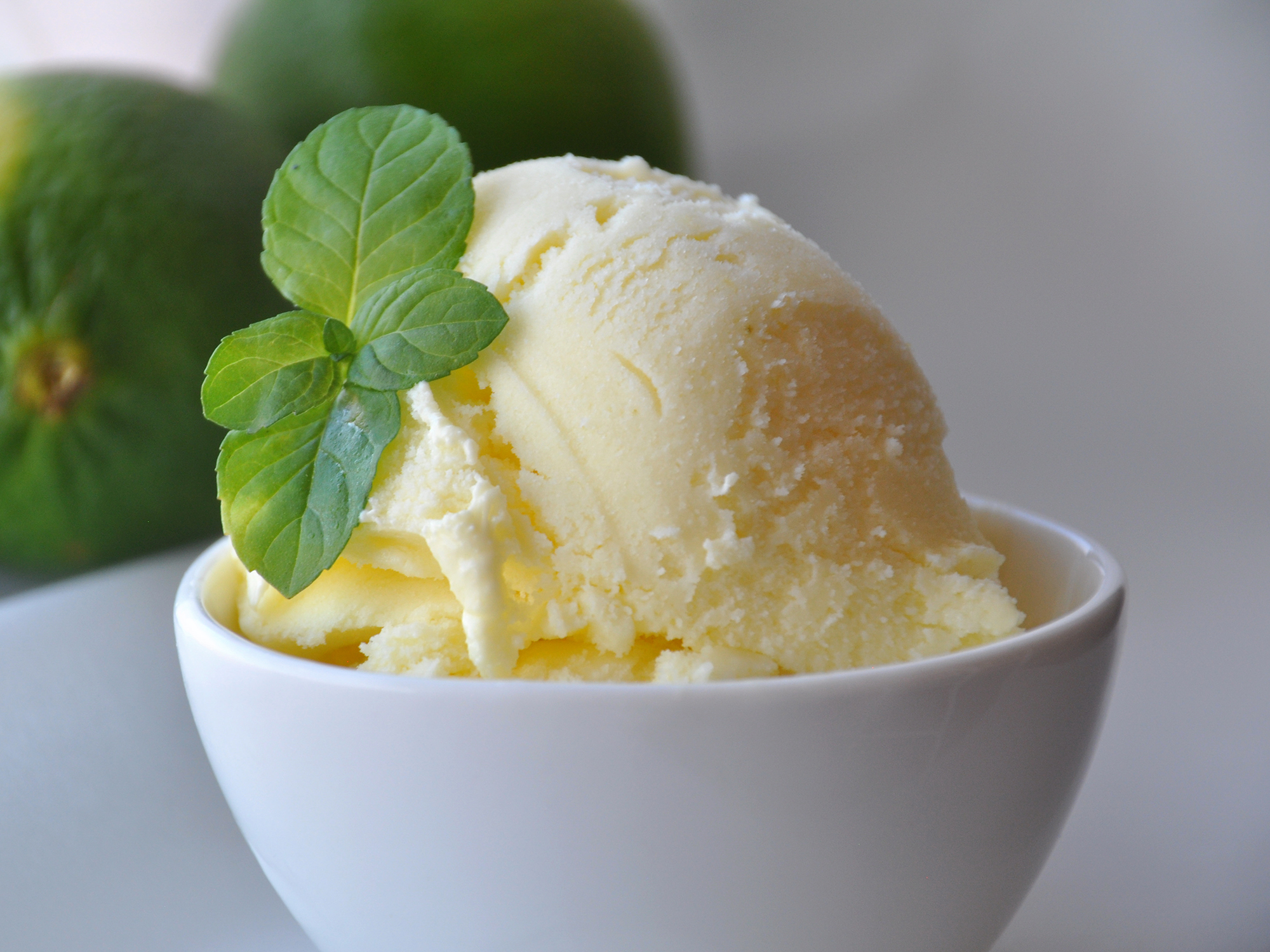 close up view of a scoop of Key Lime Ice Cream, garnished with fresh mint, in a white bowl