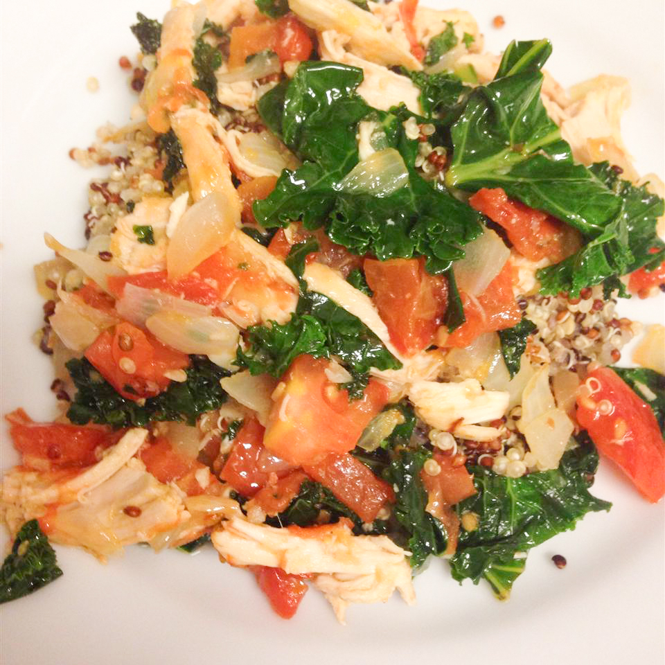 close up view of Chicken with Quinoa and Veggies, including kale and tomatoes, on a white plate