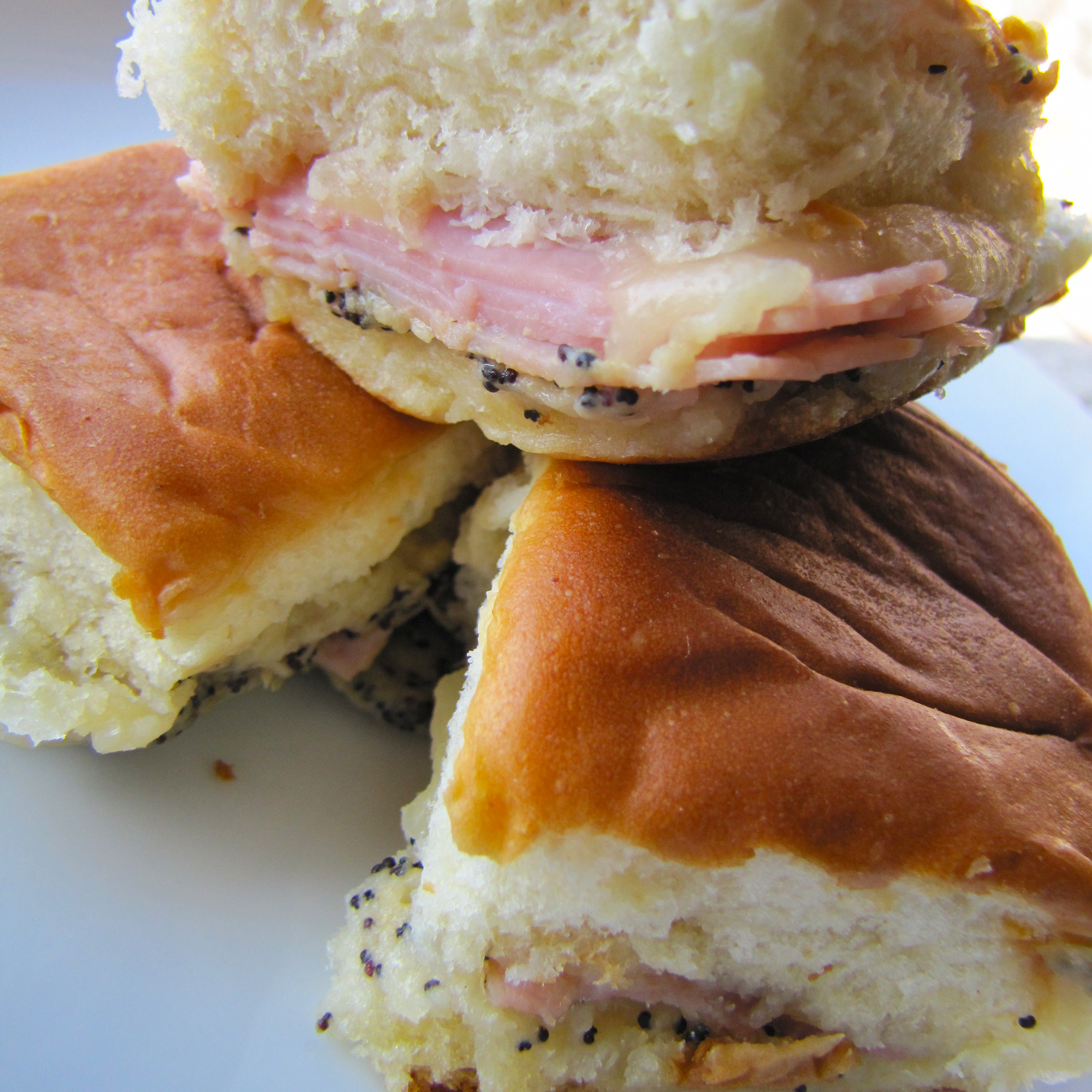 close up view of a stack of three Ham and Cheese Appetizer Sandwiches on a white plate