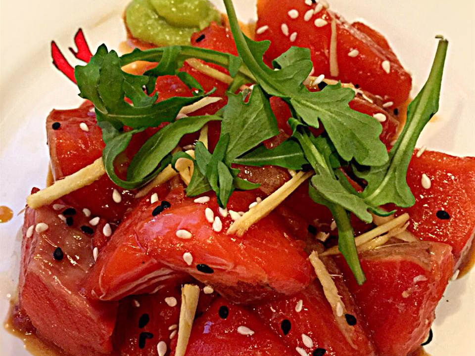close up view of Tuna Tartare garnished with arugula, sesame seeds and wasabi on a plate