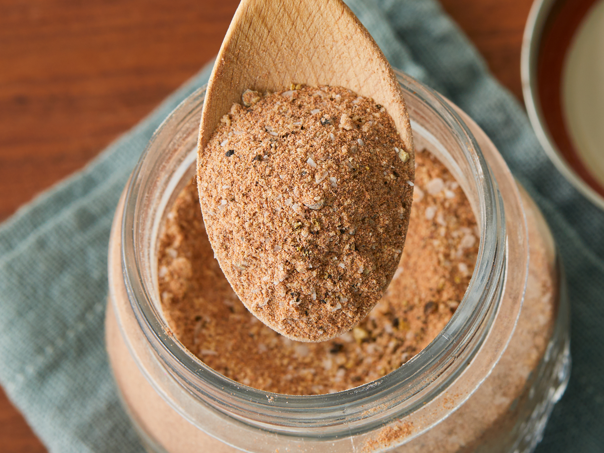 close up on a spoonful of southern style dry rub hovering over a jar full