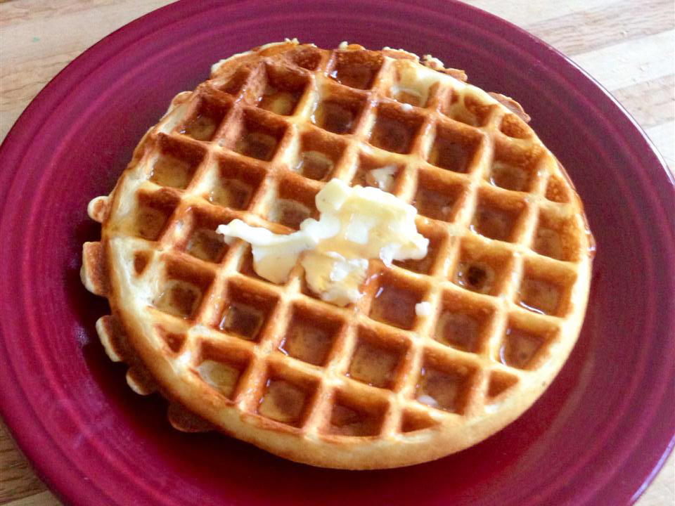 close up view of a Norwegian Waffle with butter on top, on a pink plate
