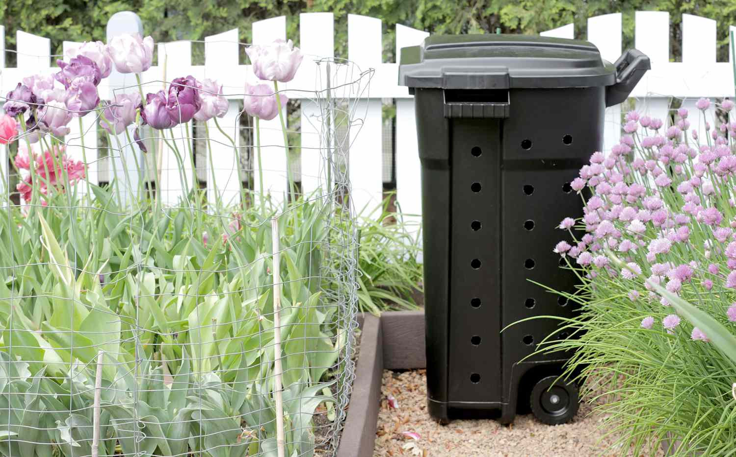 Compost bin sitting in flower garden