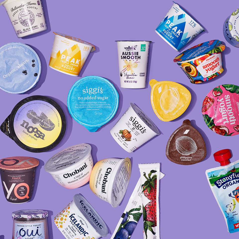 many different brands of packaged yogurt from overhead with purple background