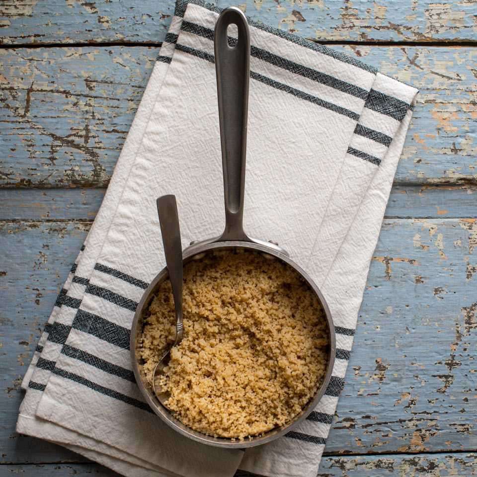 Couscous in a pot on blue wood background