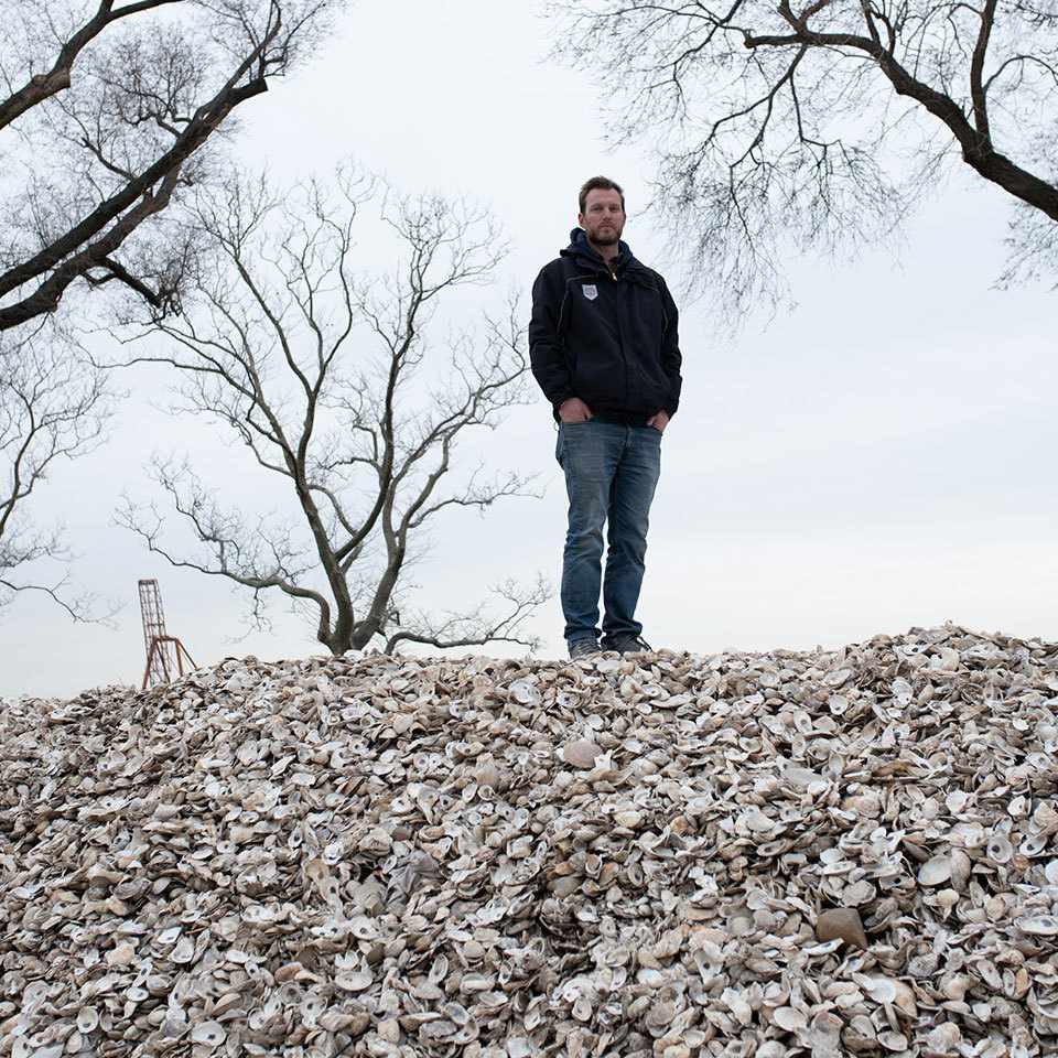 Pete Malinowski of The Billion Oyster Project stands on a hill of oyster shells