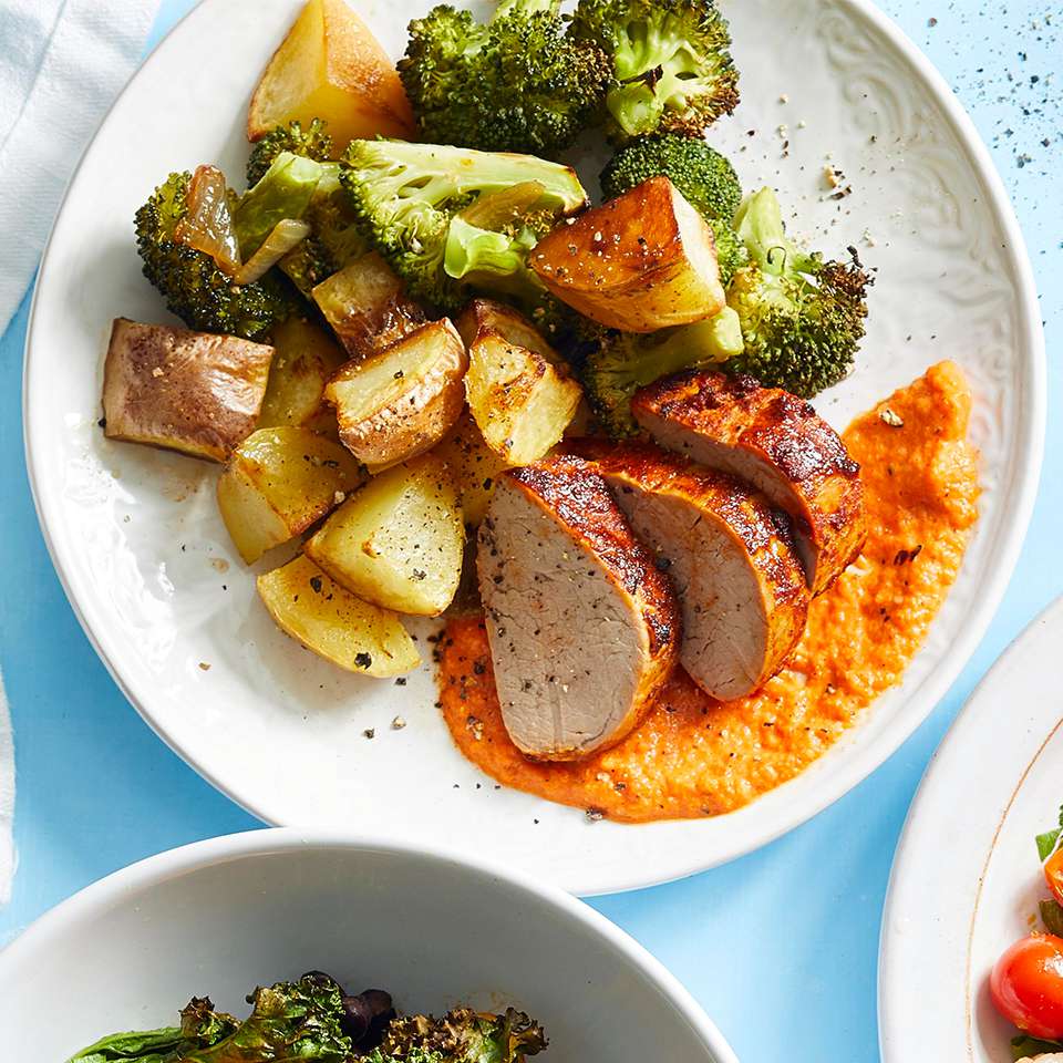 Pork, potatoes and broccoli on a white plate on a light blue background