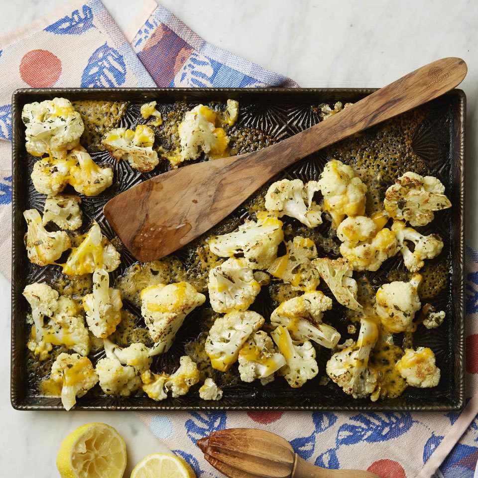 a sheet pan with cauliflower and a wooden spatula