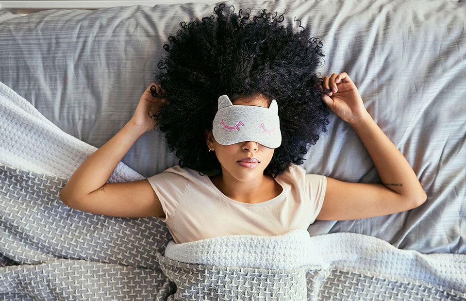 woman lying in bed with sleep mask over her eyes