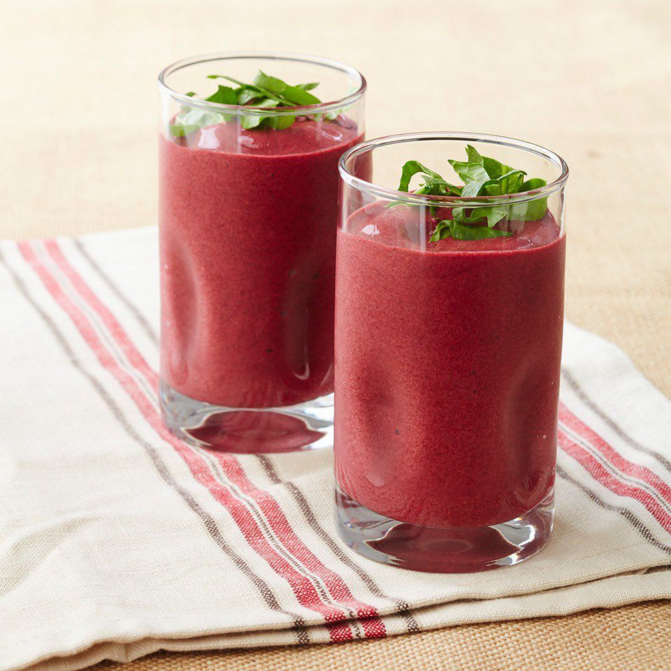 2 glasses of berry smoothies with herb garnishes
