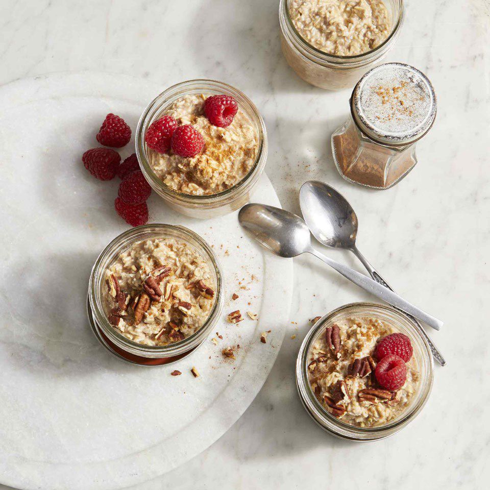jars of Cinnamon Roll Overnight oats on a countertop with spoons and raspberries