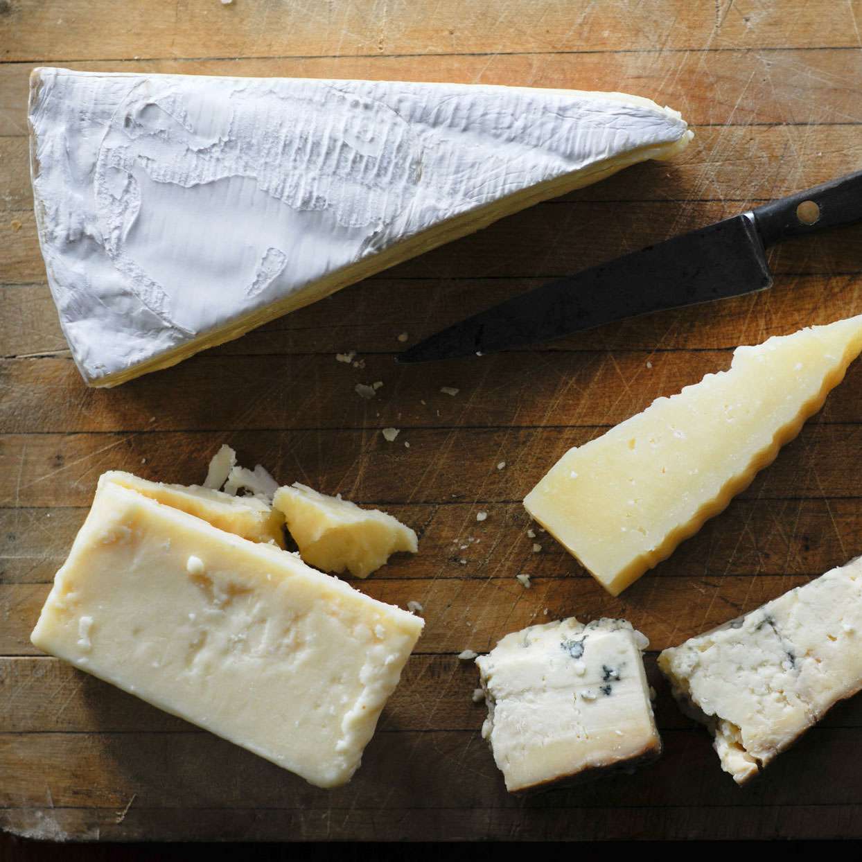 different types of cheeses on a board with a knife